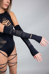 Model showcasing a black Freedom Rave Wear bodysuit paired with matching arm sleeves detailed with linear cut-outs, adding a bold and edgy style.