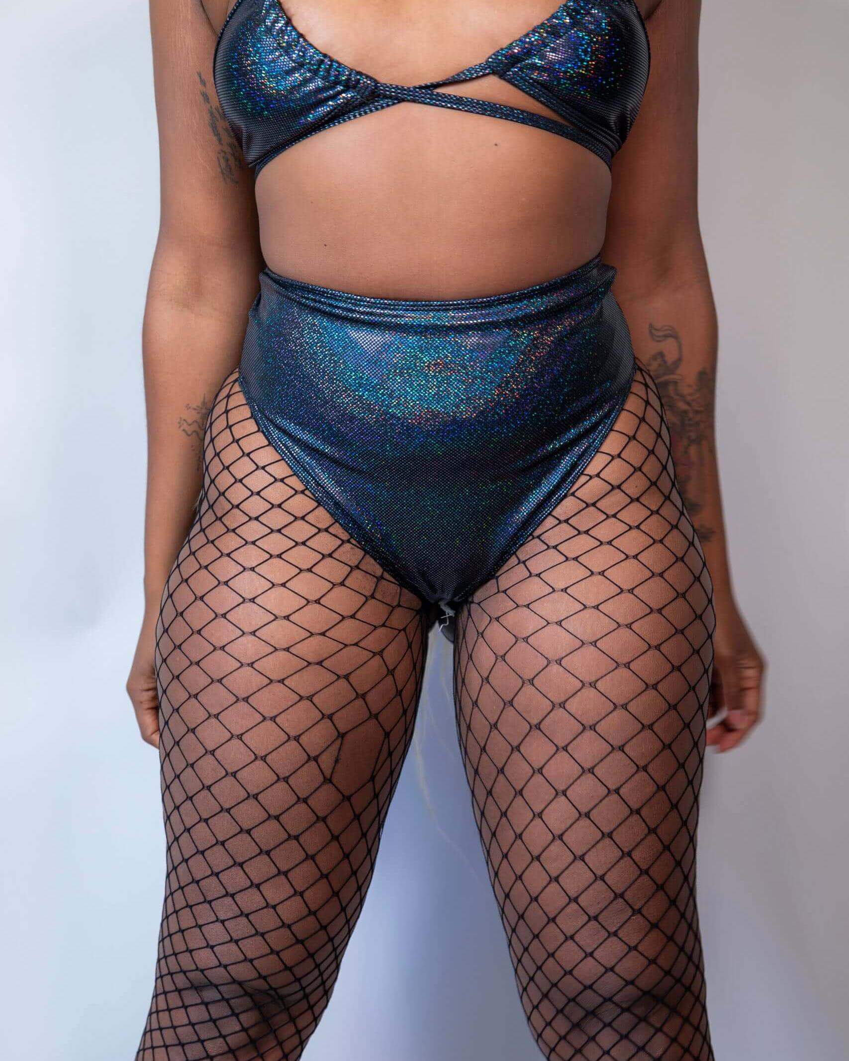 Stylish rave outfit featuring a shimmery black bikini top and high-waisted metallic bottoms with fishnet stockings.