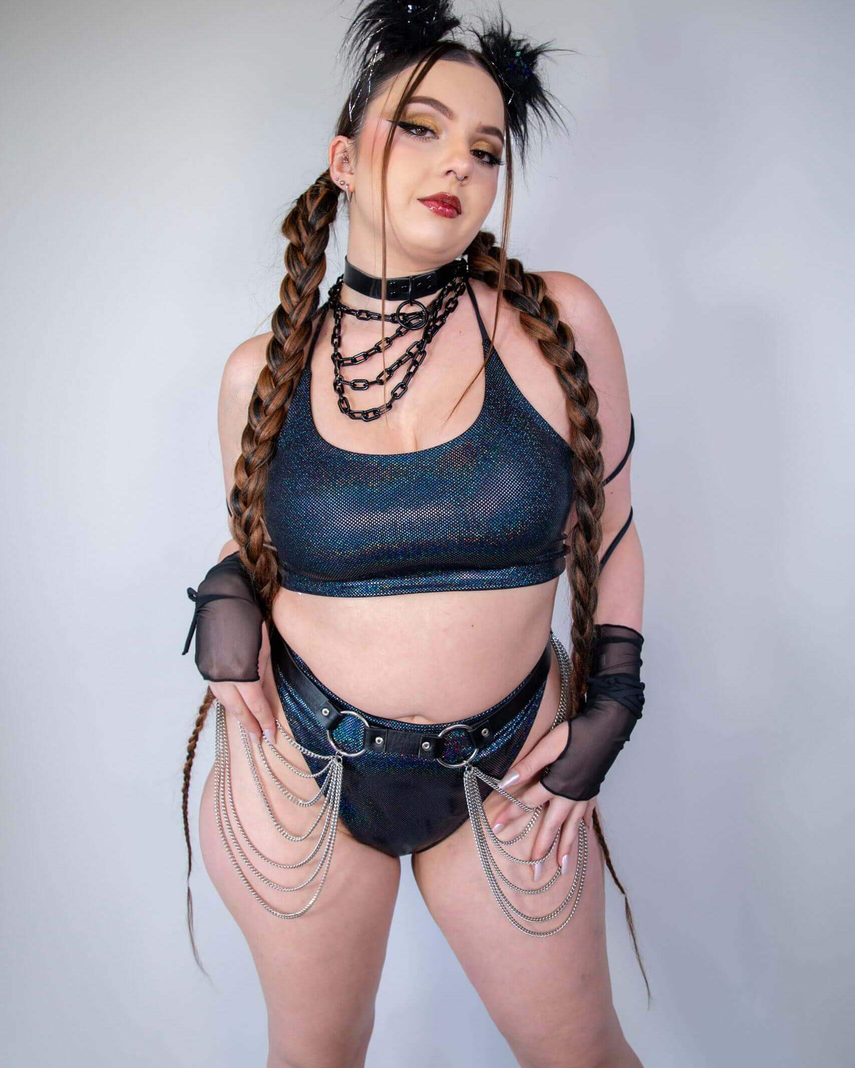 Rave outfit featuring a sparkling crop top, stylish shorts with chains, and bold hair accessories for an edgy festival look.