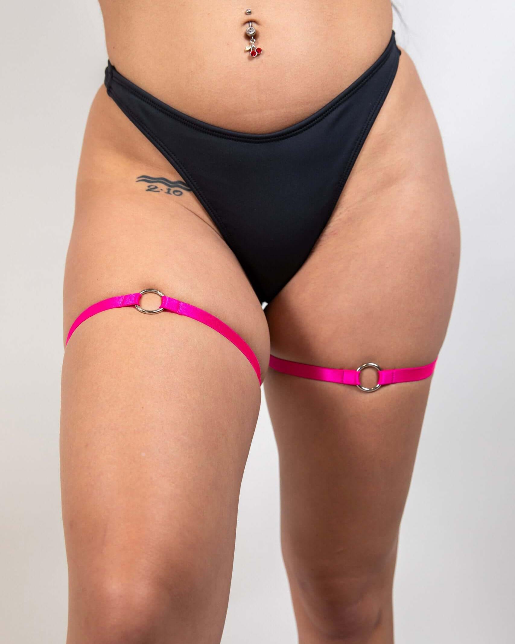 O-Ring leg garter set in pink with high-quality elastic, worn above a black bikini bottom, perfect for rave outfits.