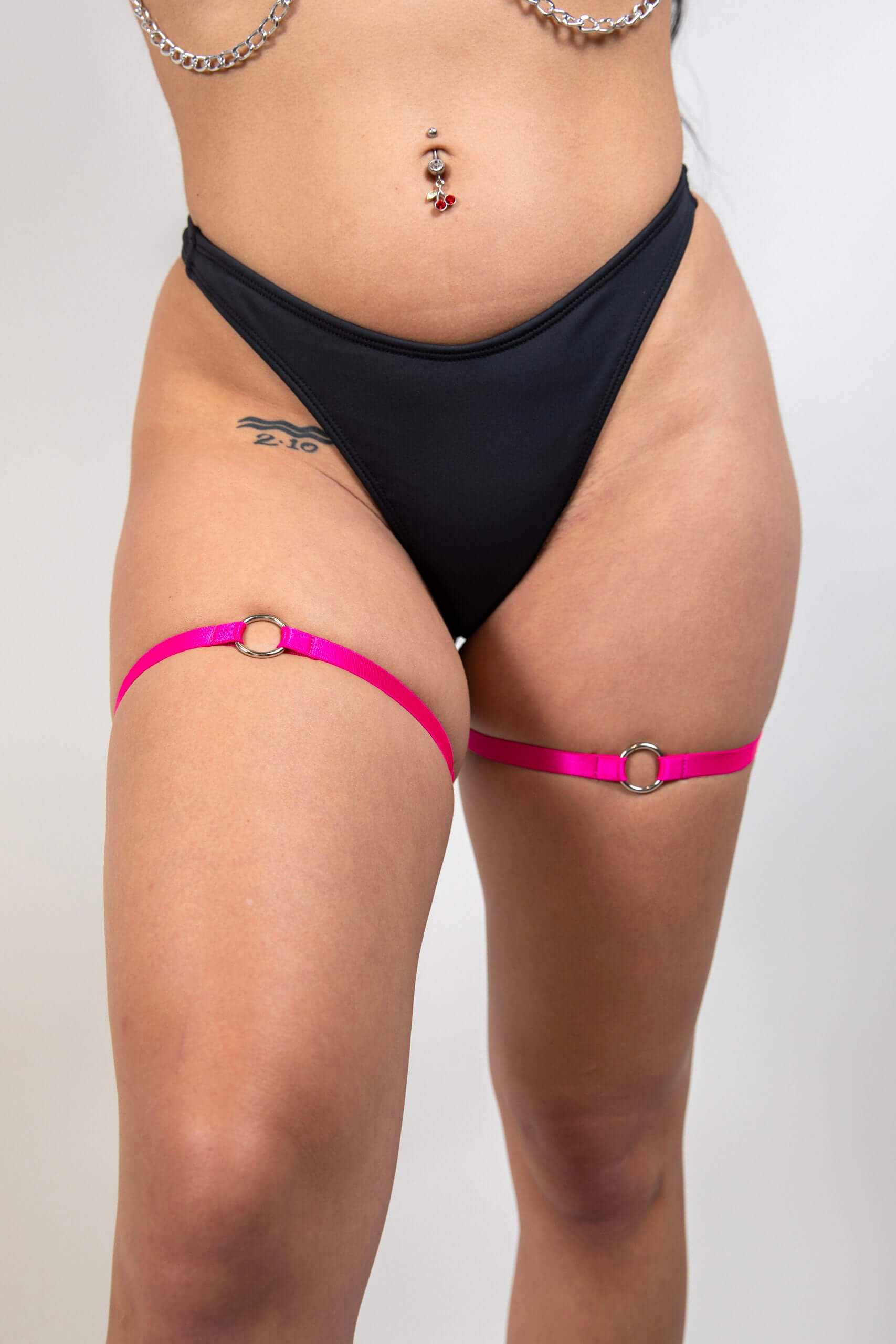 O-Ring leg garter set in pink with high-quality elastic, worn above a black bikini bottom, perfect for rave outfits.