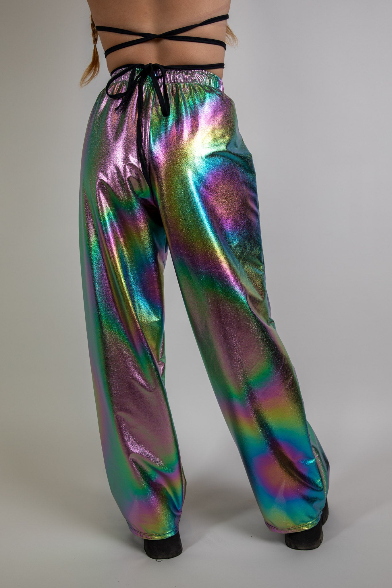 Back view of holographic swirl print rave pants, loose fit, high-waisted design, shiny multicolor finish ideal for EDM festival outfits.