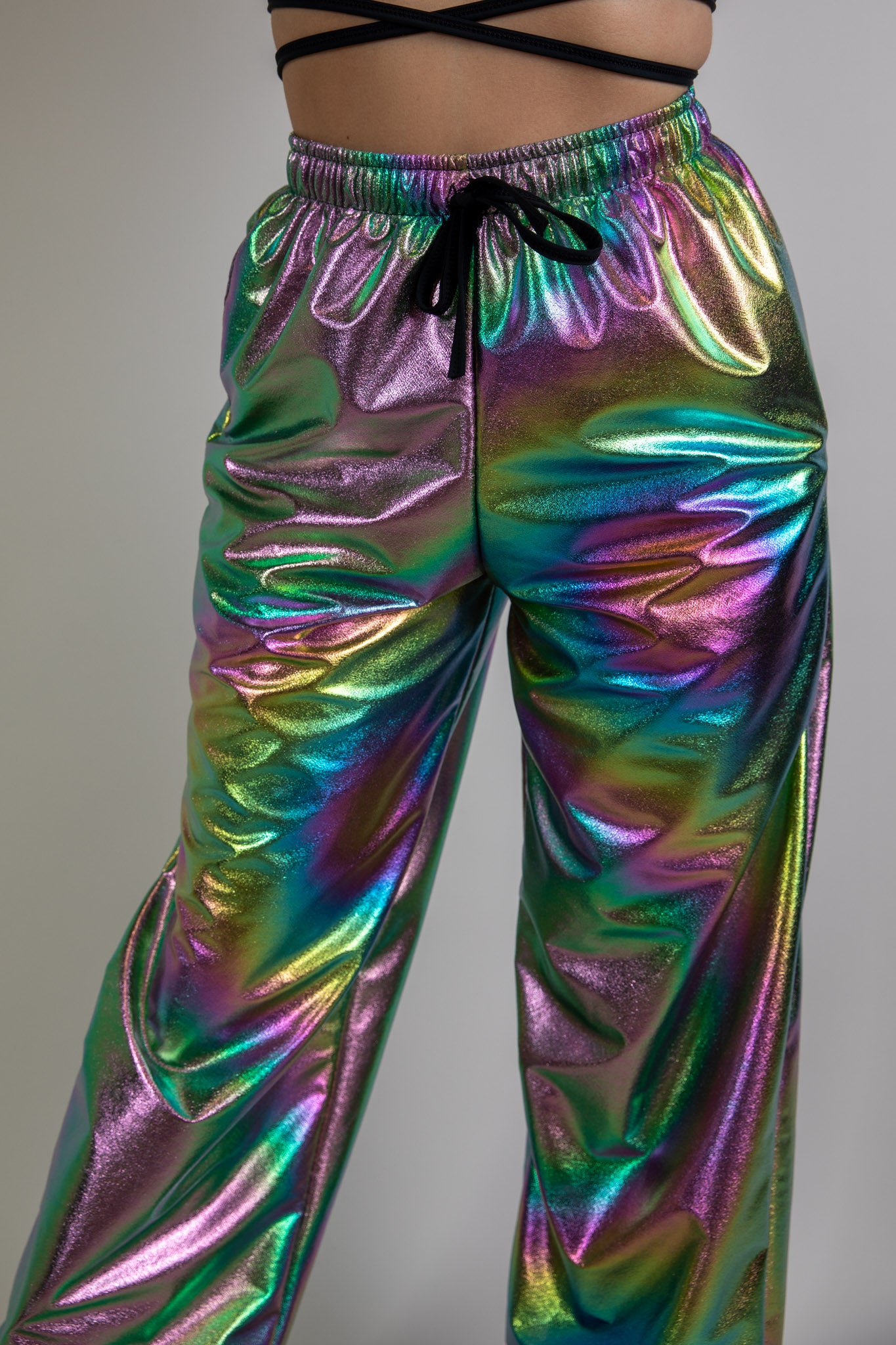 Holographic swirl rave pants, front view, vibrant reflective pattern, high-waisted design, stylish and comfortable for rave wear.