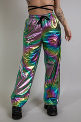 Model wearing Freedom Rave Wear’s Oil Slick Lucy Pants, high-waisted, loose-fitting with a holographic, iridescent oil slick pattern. Perfect for rave fashion, these statement festival pants offer bold colors and unique style.