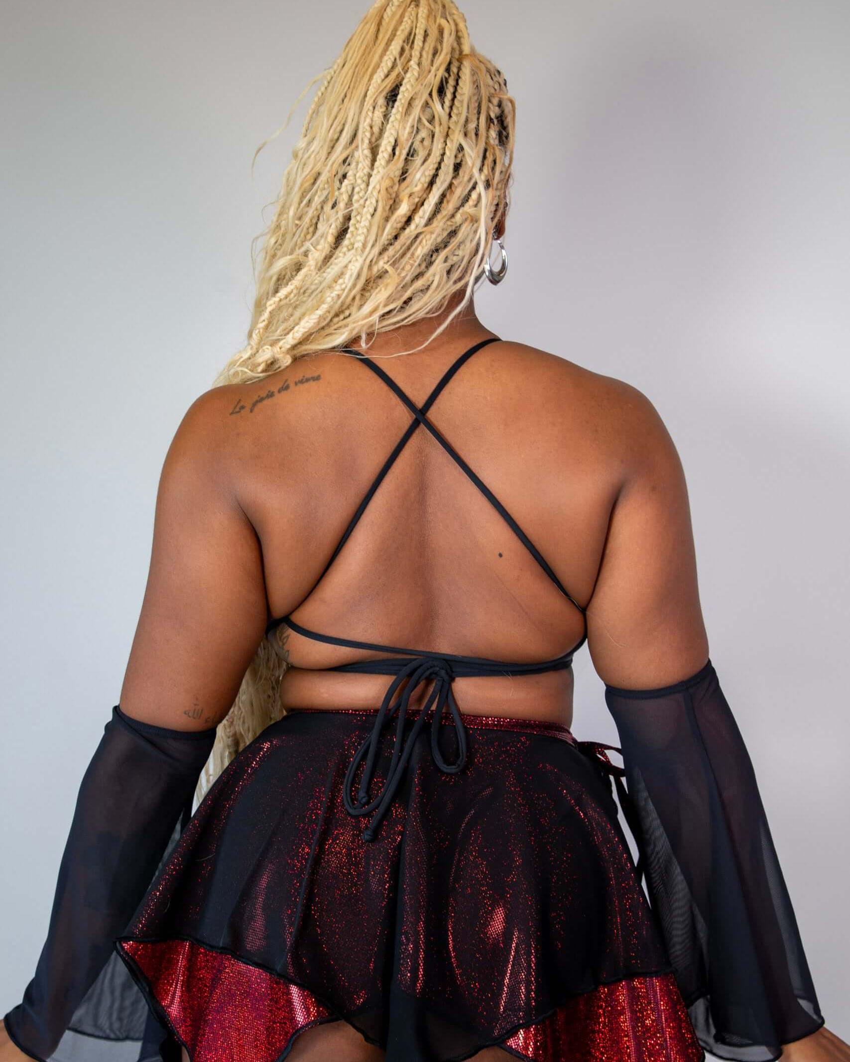 Back view of a model wearing the Phoenix Lush top with lace up design and a sparkly red skirt, suitable for rave outfits.