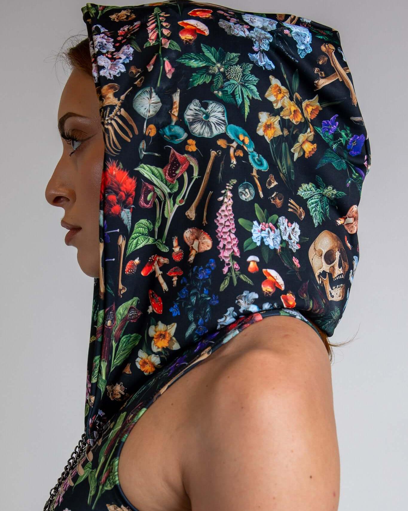 Side view of a model wearing the Poison Assassin Hood featuring bold skull and plant prints, perfect for rave outfits.