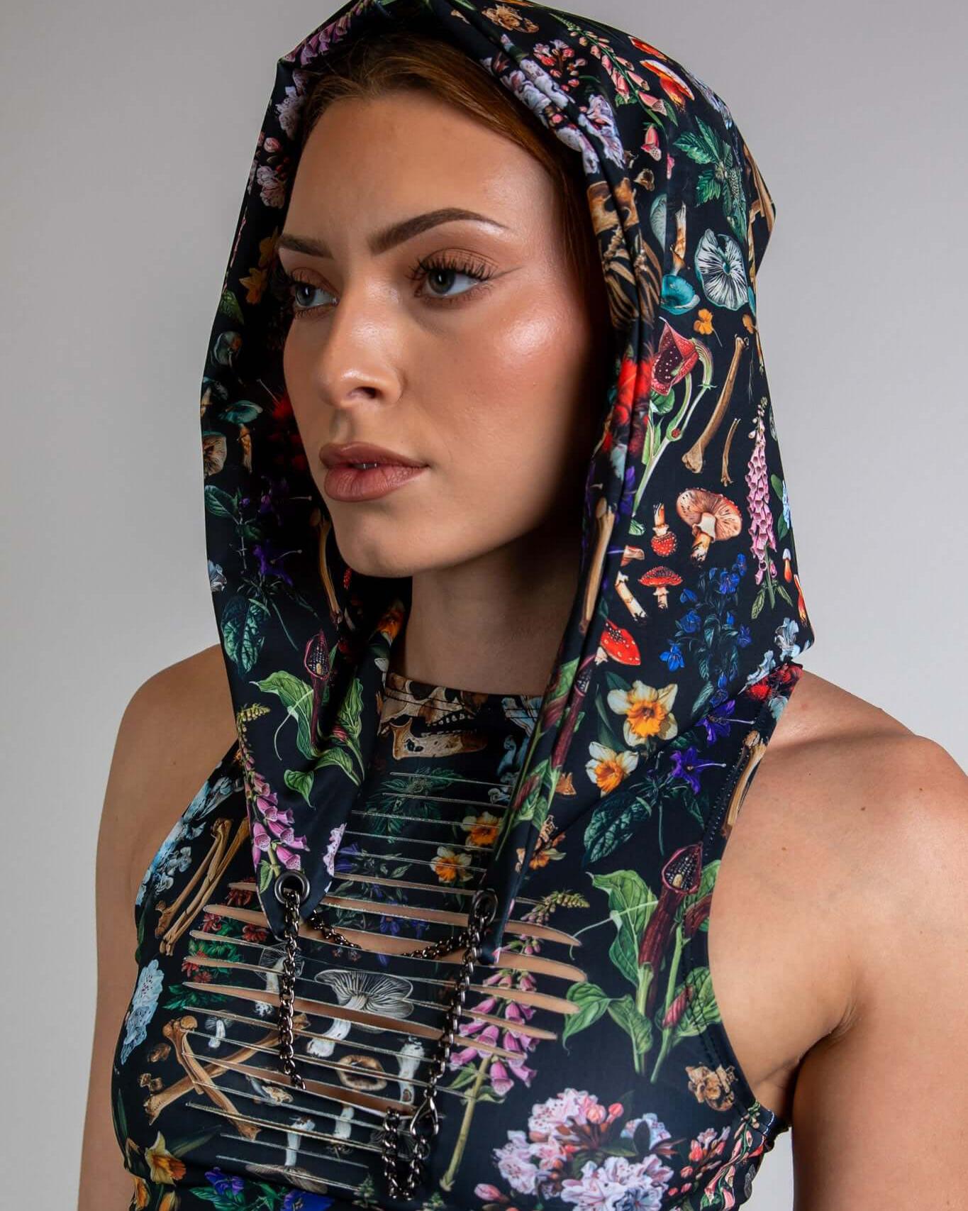 Woman wearing Poison Assassin Hood with bold skull and floral print, perfect for rave outfits and edgy streetwear.