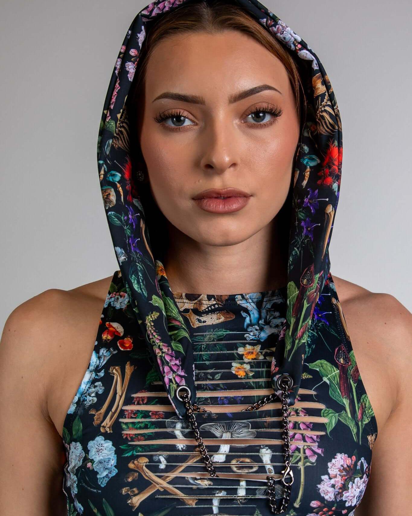 Model wearing Poison Assassin Hood with vibrant skulls and floral print, perfect for rave outfits and edgy streetwear.