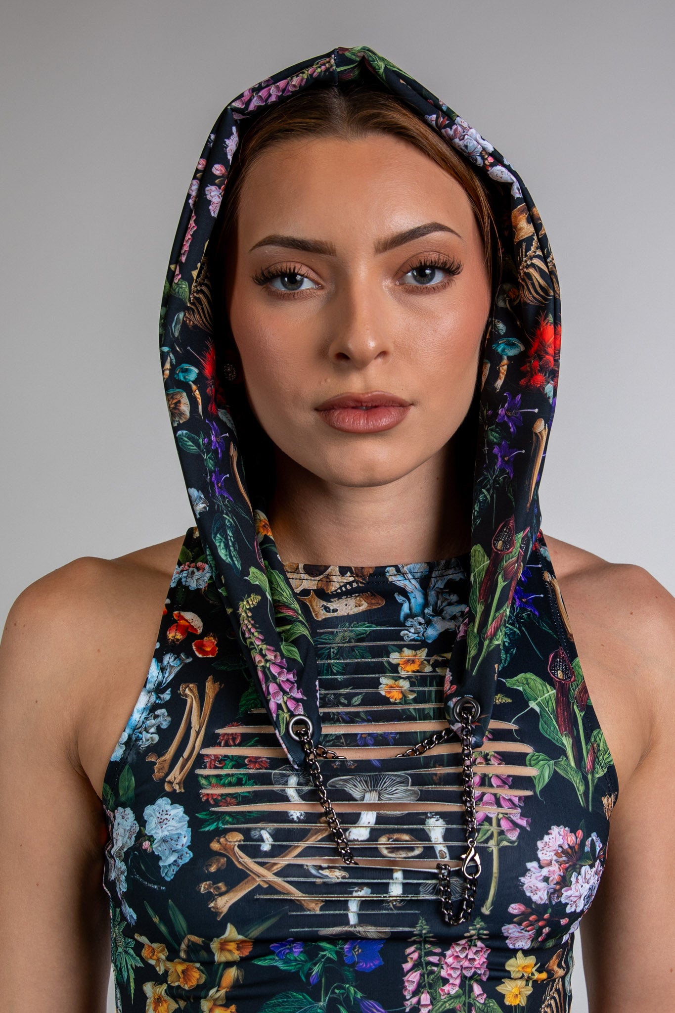 Model wearing Poison Assassin Hood with a bold, vibrant abstract design on black fabric, front view. She is also wearing matching top.