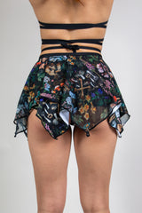 Model wearing Poison Fairy Skirt with a vibrant abstract design on black fabric, featuring flowy, multi-layered panels, back view, perfect for festival fashion.