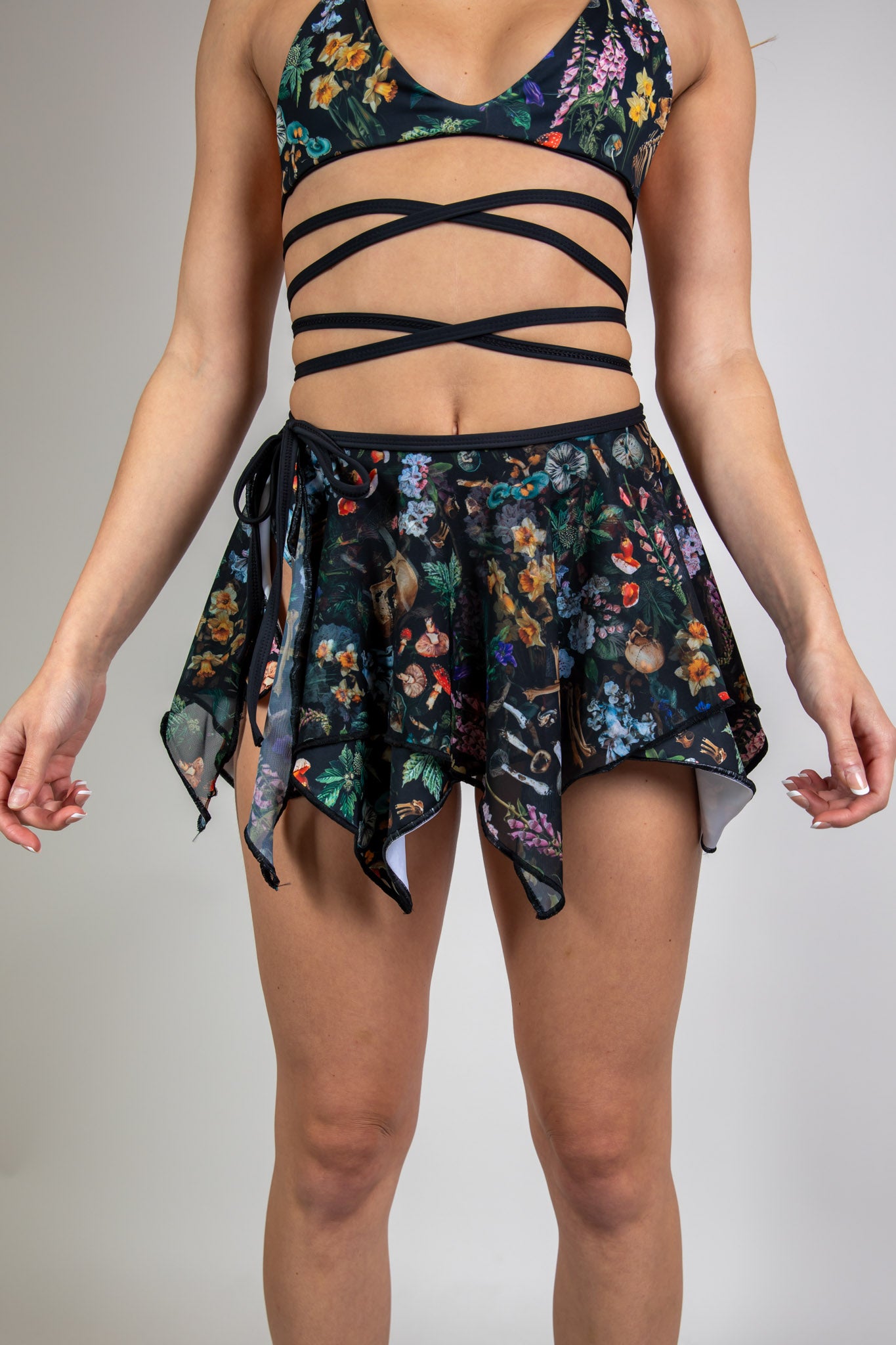 Model wearing Poison Fairy Skirt with a vibrant abstract design on black fabric, featuring flowy, multi-layered panels, front view, perfect for rave and festival fashion.