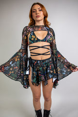 Model wearing Poison Mesh Bell Sleeves with a vibrant abstract design on sheer black fabric, perfect for rave and festival fashion, front view.