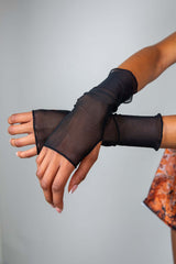 Close-up of black mesh gloves from Freedom Rave Wear, showcasing the sheer, fingerless design with a snug fit extending past the wrist.