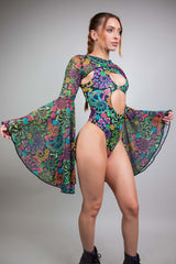 Striking pose in Freedom Rave Wear, featuring a multicolored bodysuit with daring cutouts and flowing bell sleeves.