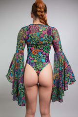 Rear view of a woman in a Freedom Rave Wear bodysuit with vivid floral patterns and extravagant bell sleeves