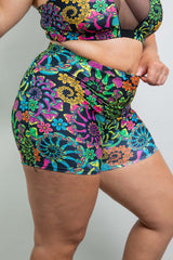 Close-up of a model wearing Freedom Rave Wear, featuring a V-Free top with a sheer detail and high-waisted rave shorts. The outfit is highlighted by its lush, colorful floral and psychedelic print, embodying the vibrant spirit of rave culture.