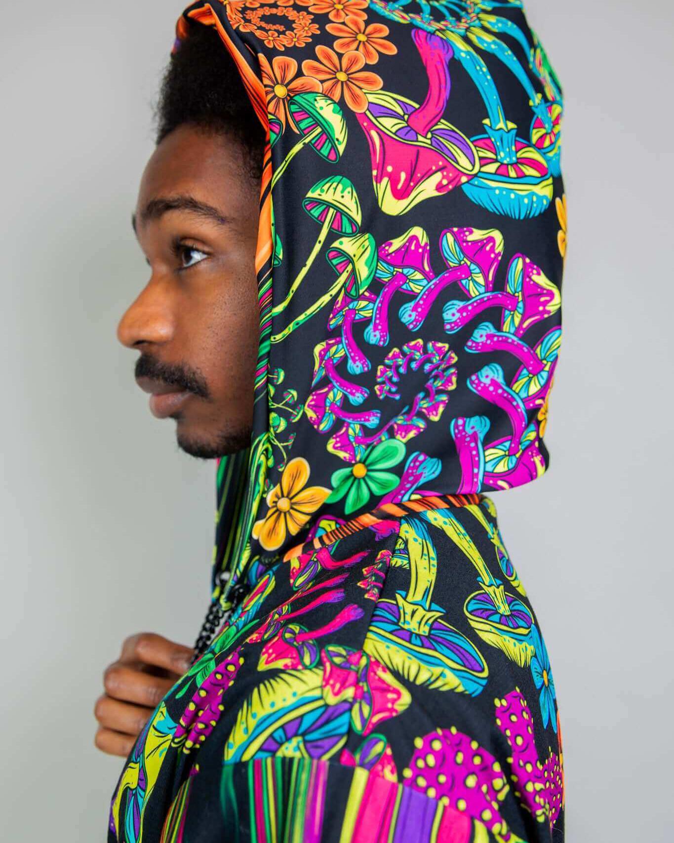 Man wearing a vibrant PsyBloom Assassin Hood with a floral design, perfect for rave outfits and festival wear.