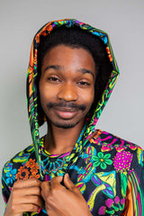 Close-up portrait of a smiling man wearing a Freedom Rave Wear hood with a kaleidoscopic floral pattern.