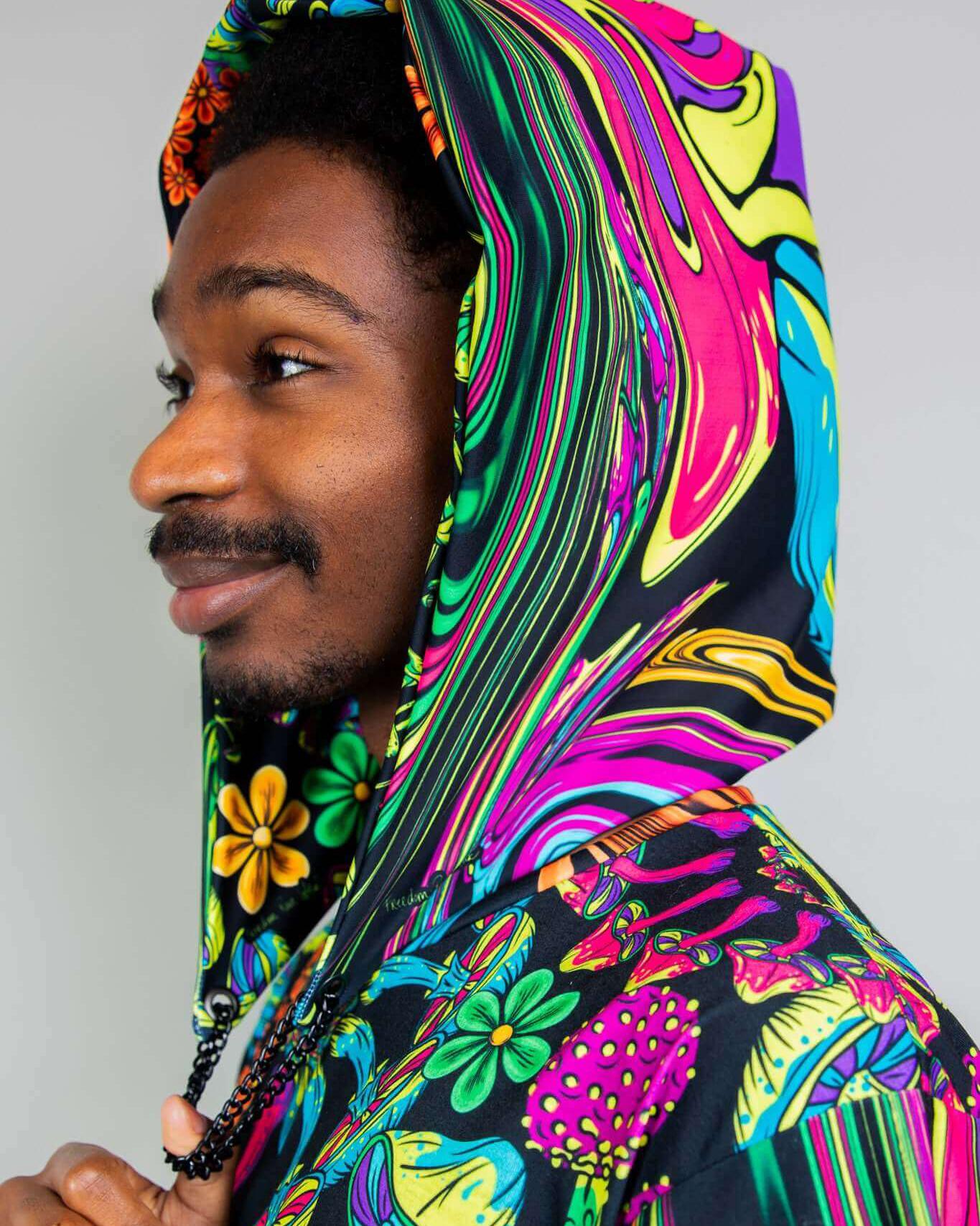 Man wearing colorful PsyBloom Assassin Hood, showcasing vibrant patterns and festival style. Perfect for rave outfits.