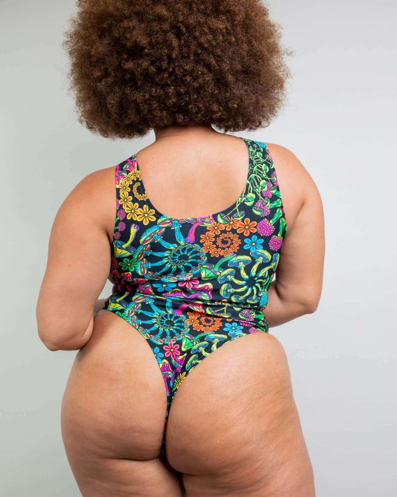 Plus-size model showcasing a colorful floral keyhole bodysuit from the back, perfect for rave outfits.