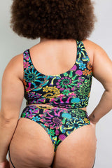 Rear view of a model wearing Freedom Rave Wear's floral tank top and high-waisted bikini bottoms, featuring bold, psychedelic patterns ideal for vibrant rave attire.