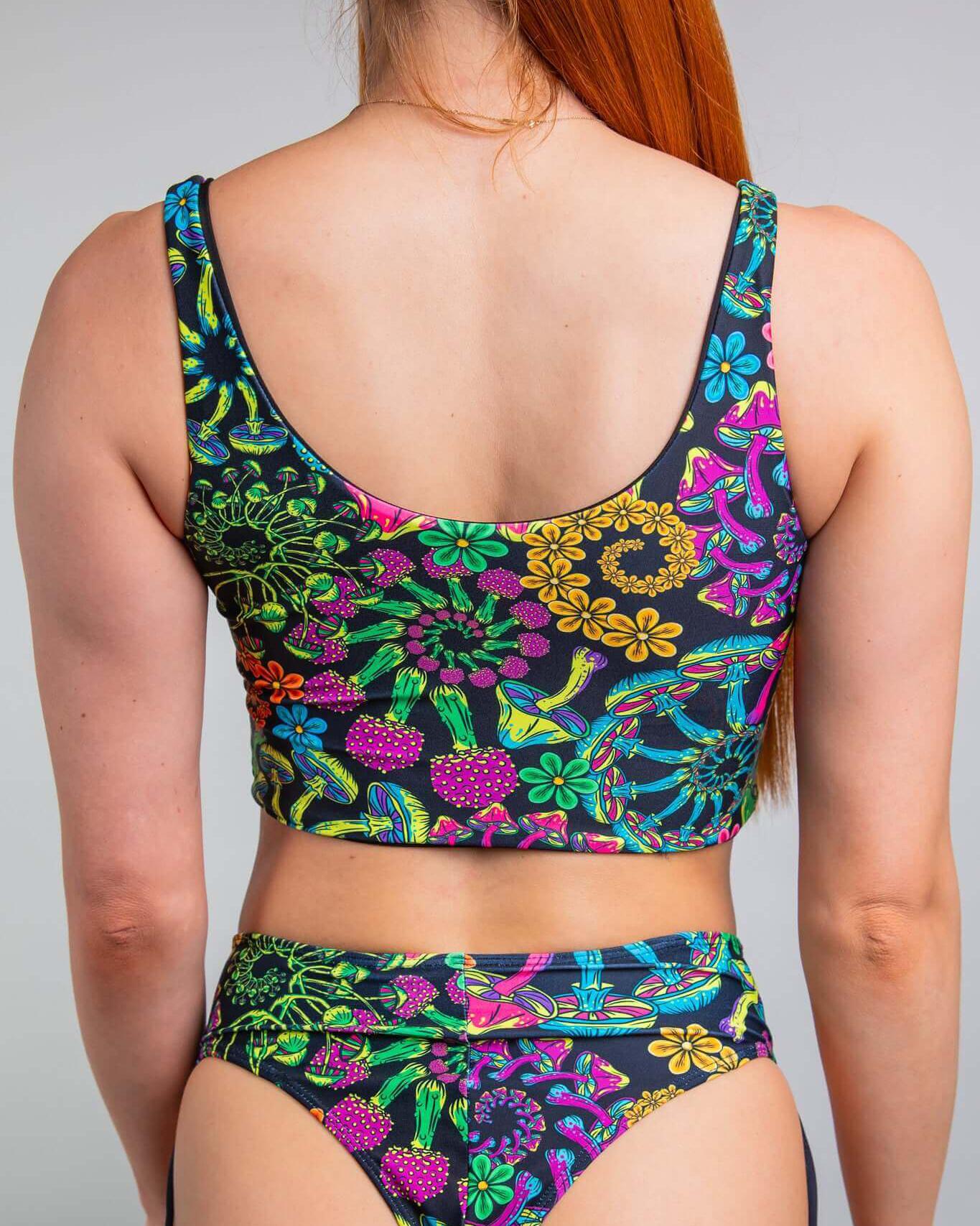 Back view of a woman wearing a colorful floral PsyBloom Lace Up Top, showcasing vibrant patterns perfect for rave outfits.