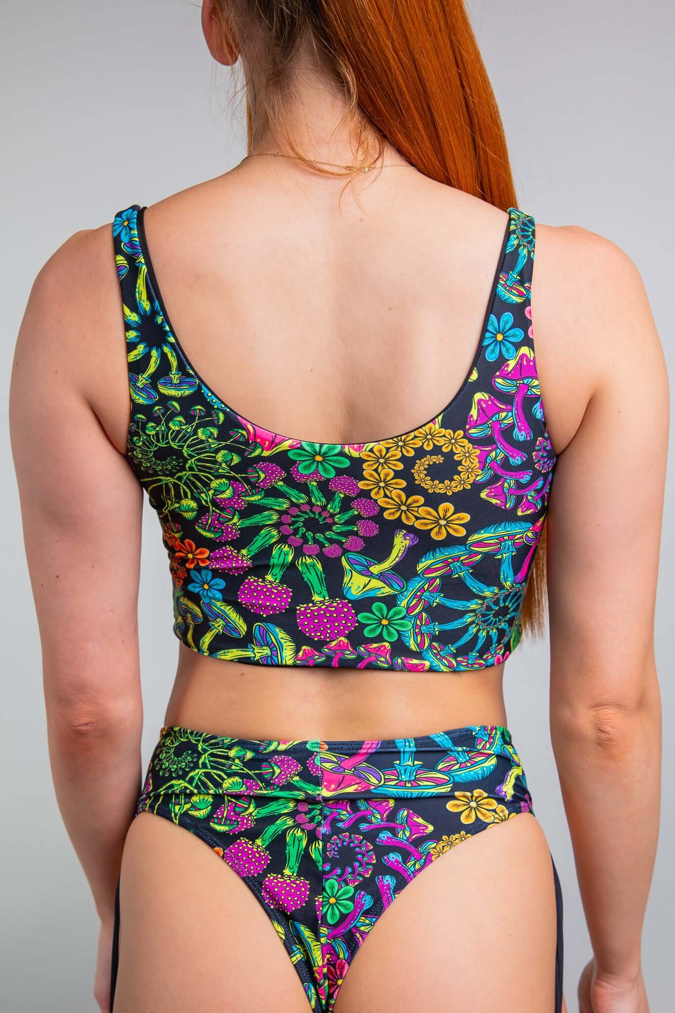 Rear view of a model in Freedom Rave Wear's floral tank top and matching high-waisted bikini bottoms, displaying an intricate, colorful pattern ideal for dynamic rave fashion