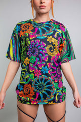 Model in Freedom Rave Wear's oversized t-shirt featuring a bright and colorful psychedelic floral print, designed for a casual yet vibrant rave attire, styled with visible high-waisted rave bottoms.