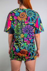 Rear view of a model in a Freedom Rave Wear oversized t-shirt with a vibrant, multicolored floral pattern, offering a loose and comfortable fit, ideal for a stylish yet casual rave appearance.
