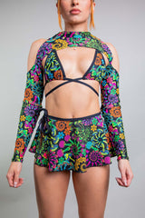 Frontal view of a model in Freedom Rave Wear with crisscrossed bikini top and spectra sleeves, featuring a vivid neon print, creating a statement rave outfit.