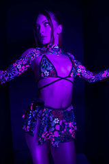 Model in Freedom Rave Wear featuring a vibrant floral bikini top and matching swirl skirt under purple lighting, presenting a daring and fashionable choice for rave enthusiasts.