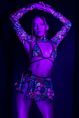 Raver in Freedom Rave Wear's UV-reactive psybloom bikini top with matching spectra long sleeves and swirl skirt, glowing under blacklight.