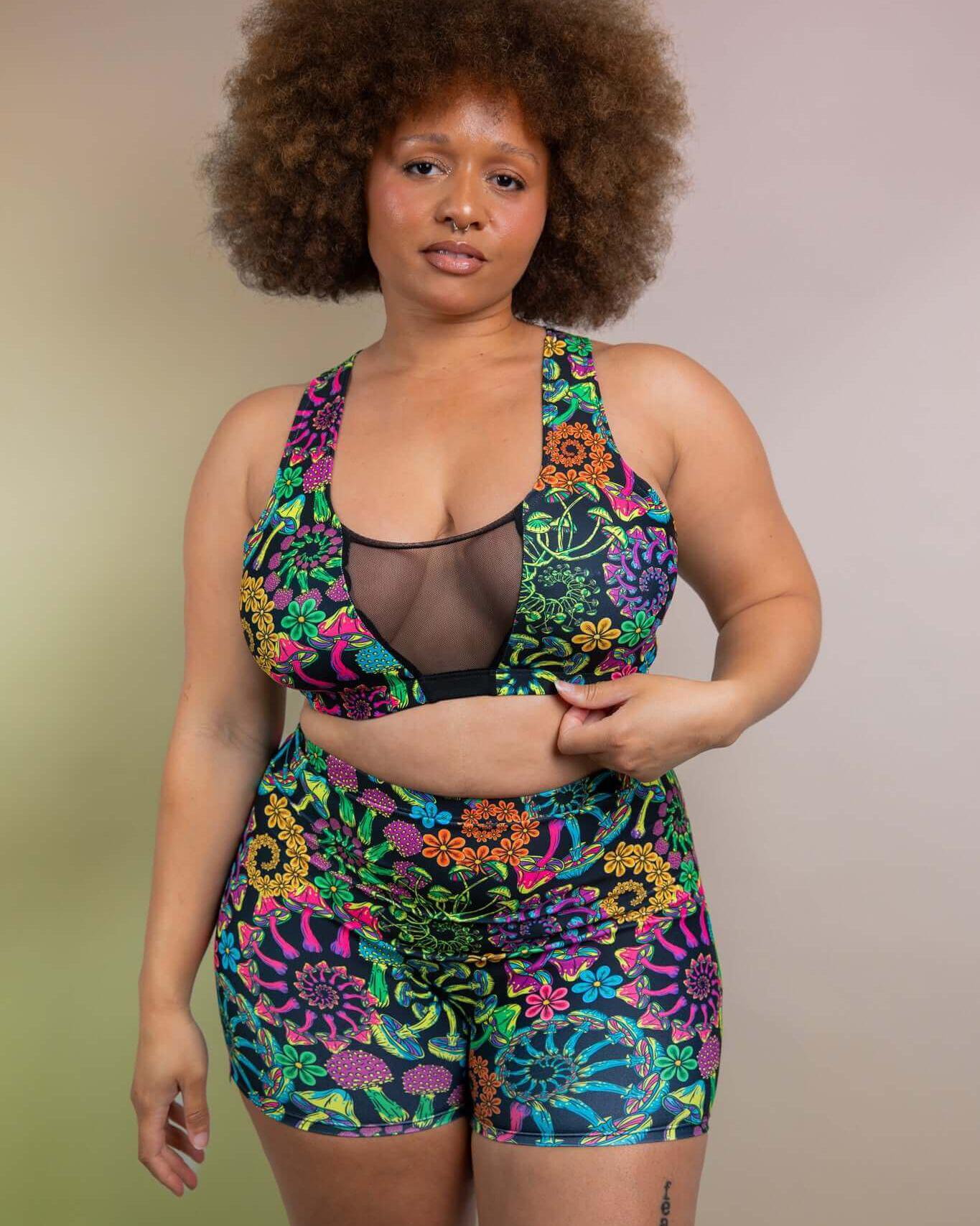 Model in colorful PsyBloom High Waist Shorts and matching top, showcasing rave outfits with vibrant patterns.