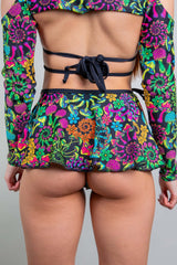 Back view of a vibrant Freedom Rave Wear psybloom swirl skirt, tied at the waist, showcasing the lively floral rave pattern.