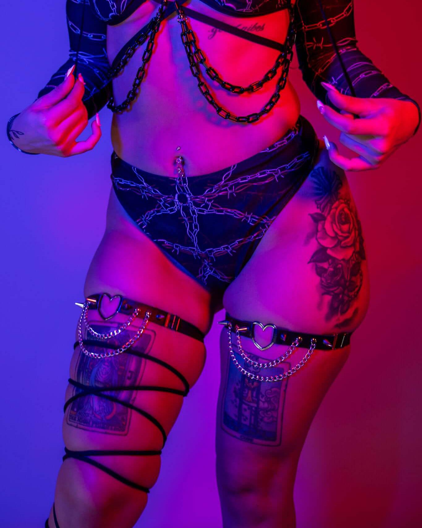 Model wearing the Purgatory High Waisted Thong with chain details and bold accessories, styled for rave outfits.