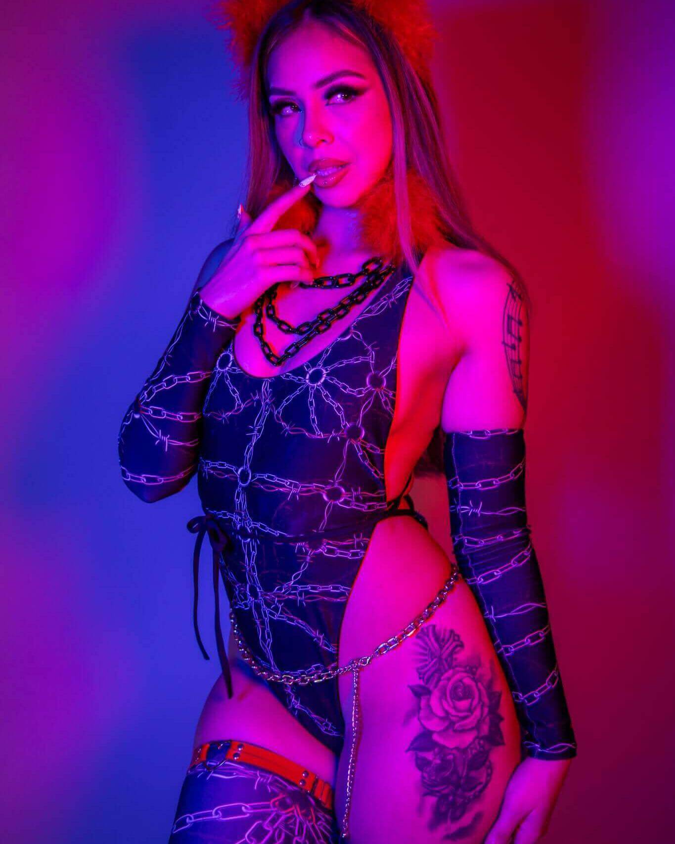 Model showcasing the Purgatory Temptation Cheeky One Piece, featuring chain graphics and bold styling against vibrant background.