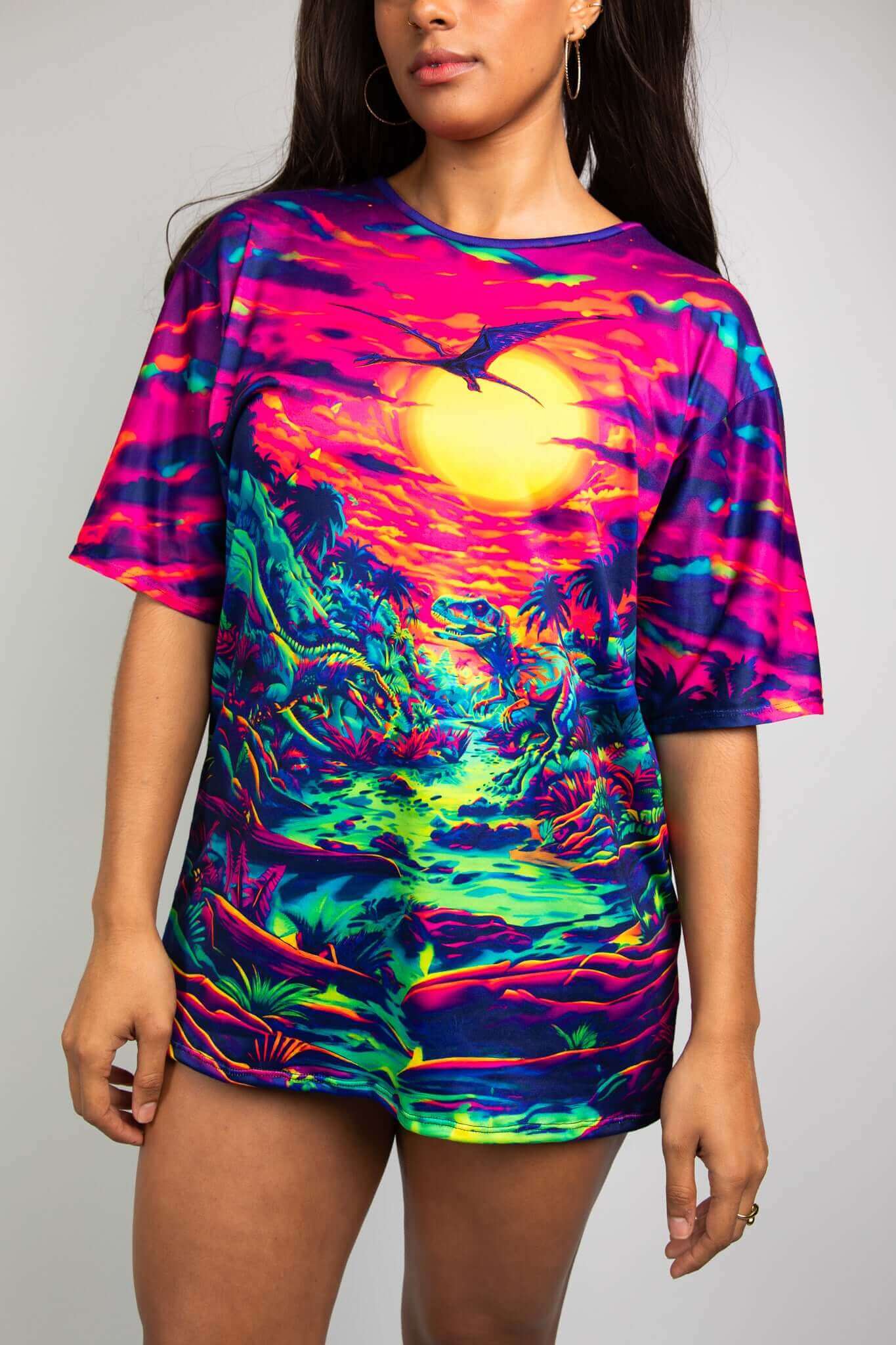 Model wearing eye-catching Freedom Rave Wear t-shirt with a vivid dinosaur scene under a neon sunset, ideal for raves.