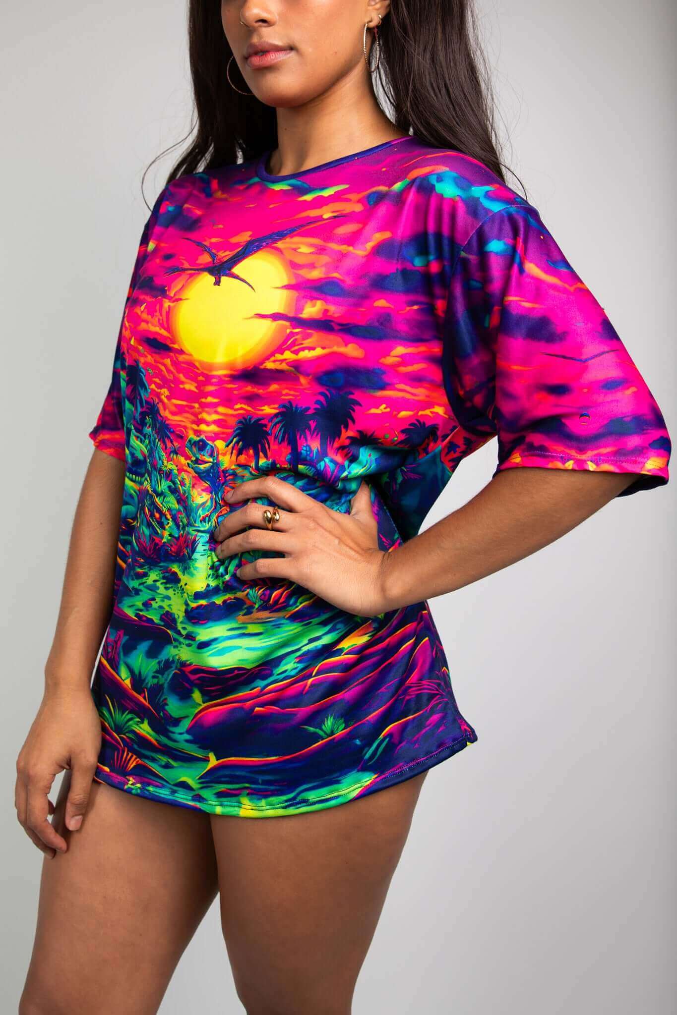 Model wearing Freedom Rave Wear t-shirt with a vivid dinosaur scene under a neon sunset, ideal for bold rave outfits.