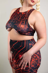 Side view of model in Freedom Rave Wear, featuring a red and black circuit-pattern top and shorts, accented with braided hair