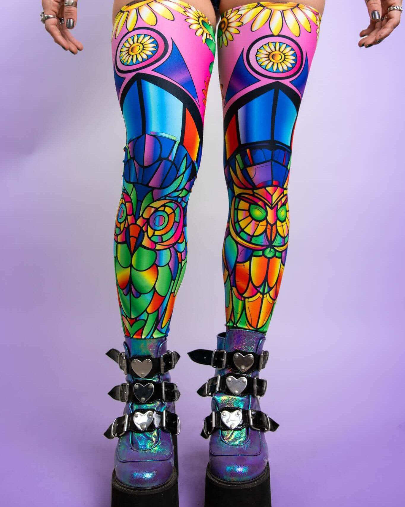 Vibrant neon leg sleeves featuring psychedelic owls and flowers, perfect for rave outfits, styled with striking platform boots.