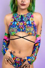 An up close photo of a girl wearing a rainbow stained glass printed crop top with black ties.