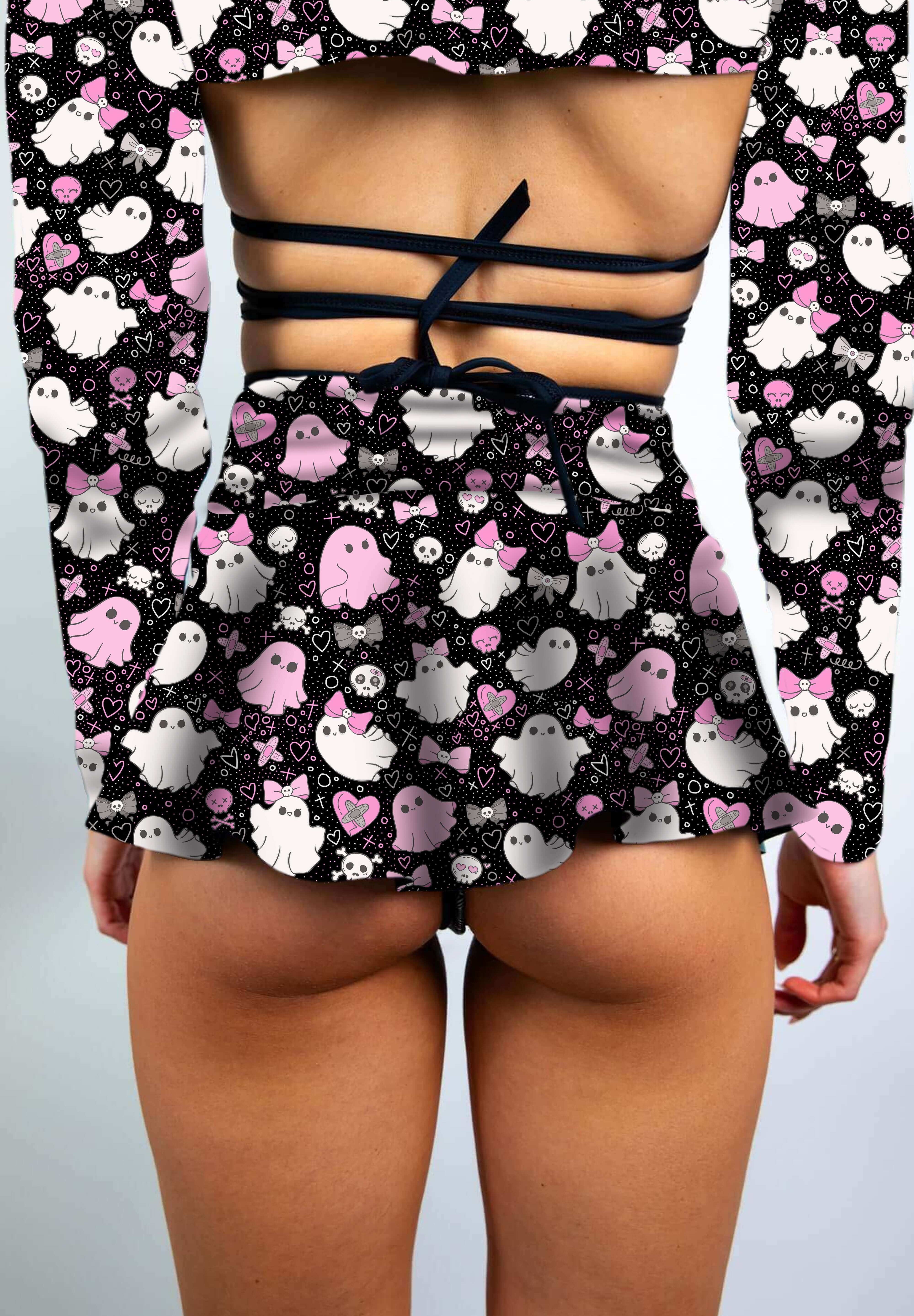 Close-up of a model in a black skater skirt with pink and white spooky ghost print, styled with a cutout crop top.