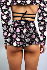 Close-up of a model in a black skater skirt with pink and white spooky ghost print, styled with a cutout crop top.