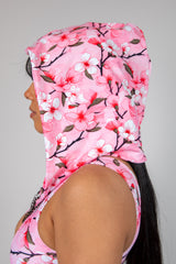 Side view of a woman wearing a Sakura Assassin Hood with pink cherry blossom design, perfect for rave outfits.