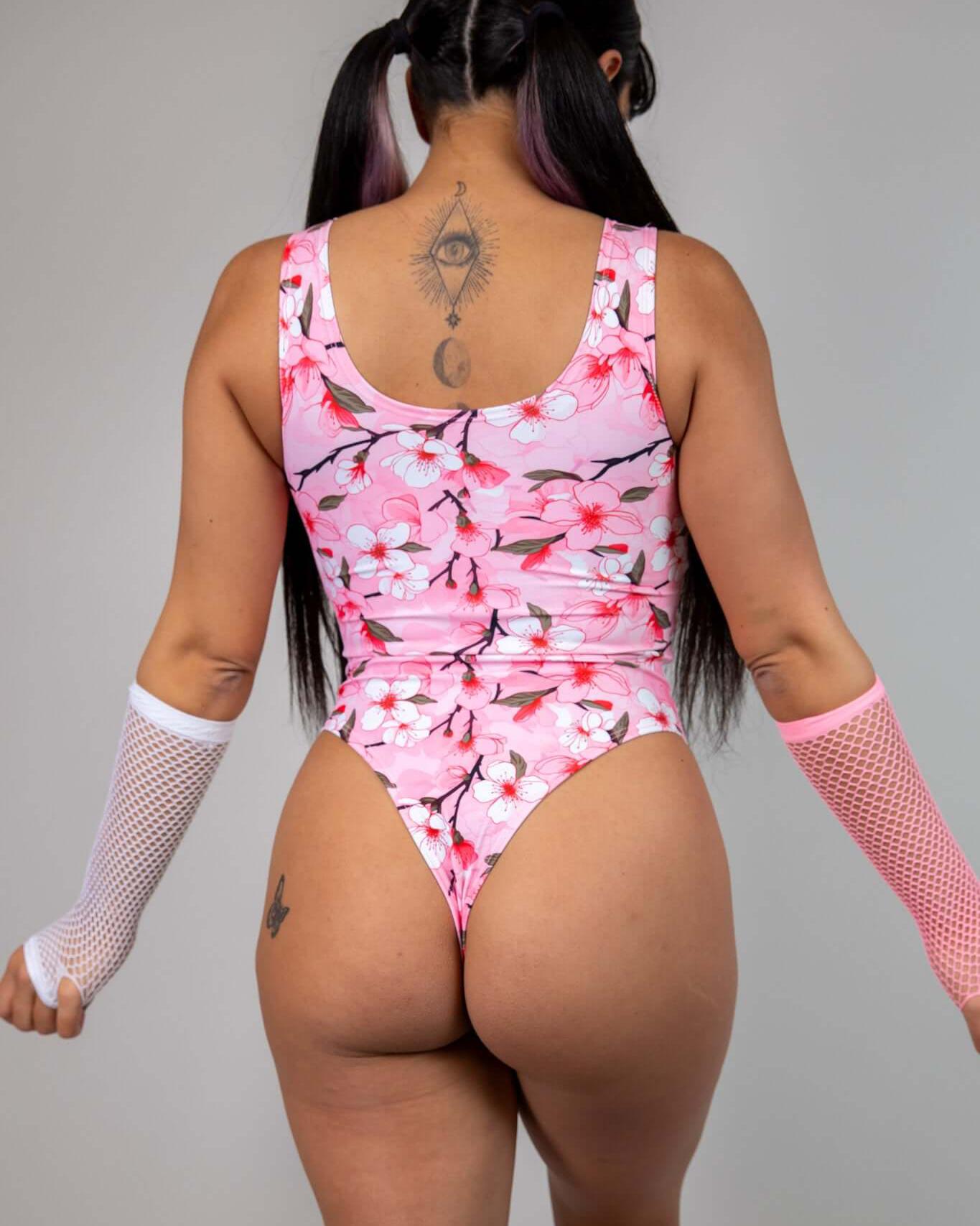 Model wearing pink cherry blossom keyhole bodysuit, showcasing back design suitable for rave outfits.