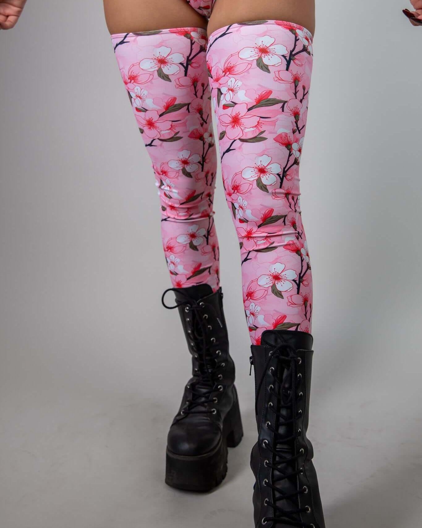 Sakura leg sleeves with pink cherry blossom design, perfect for rave outfits, paired with black combat boots.