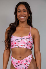 Model wearing the Pink cherry blossom print crop top with white and pink blossom design, adjustable straps. Perfect for rave fashion.