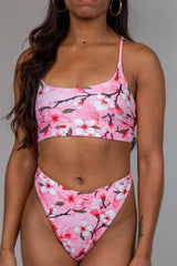 Pink cherry blossom print crop top with white and pink floral design, adjustable straps, front view, perfect for rave outfits.