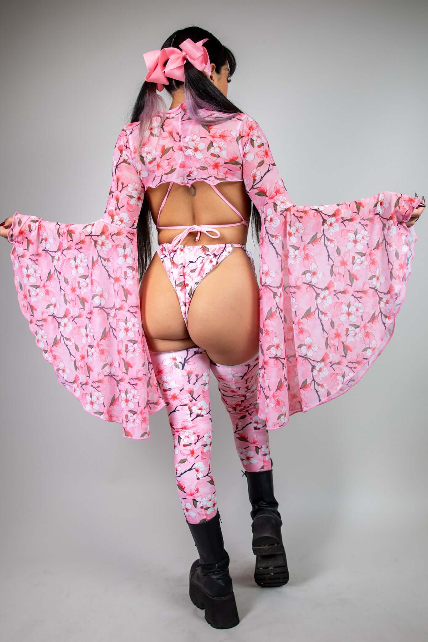 Back view of pink mesh bell-sleeve top with white and pink cherry blossom print, paired with matching leggings, perfect for festivals.