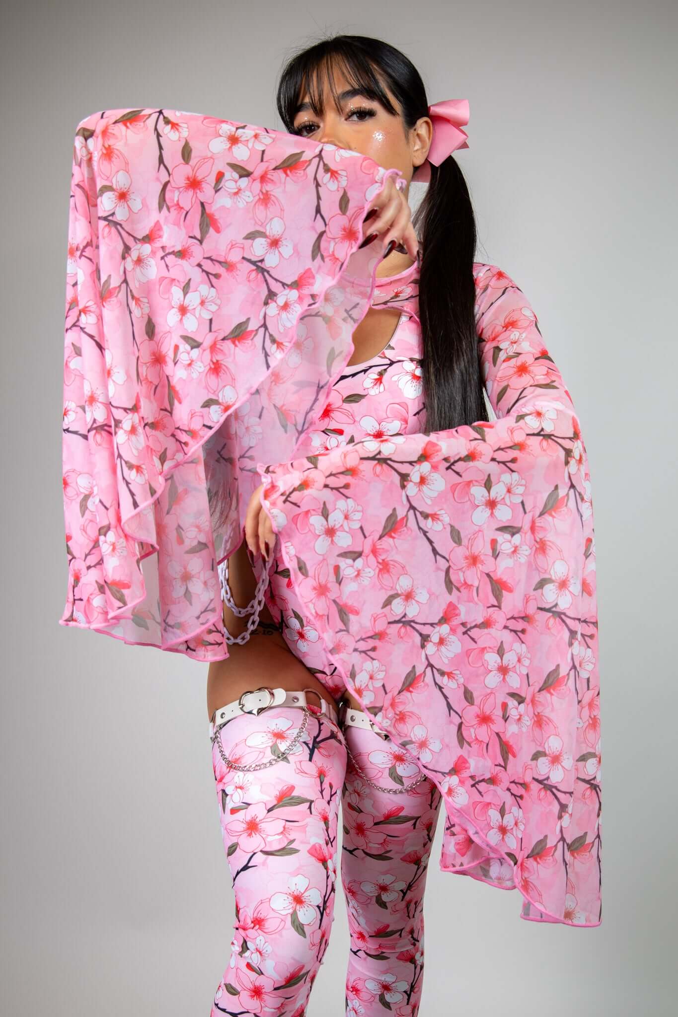 Pink mesh bell-sleeve top with flowing white and pink cherry blossom print, styled with matching leggings, perfect for rave looks.